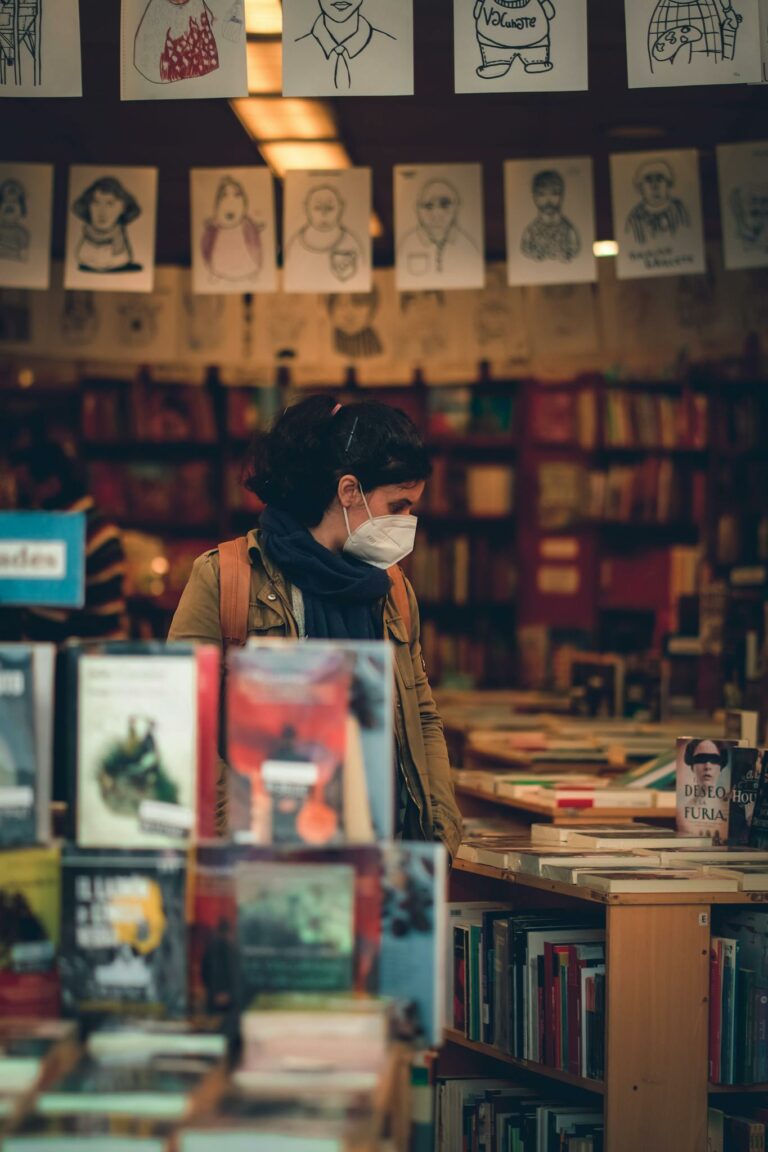 A woman wearing a face mask explores a bookstore in Adrogué, Argentina, showcasing safety and literature in a cozy setting.